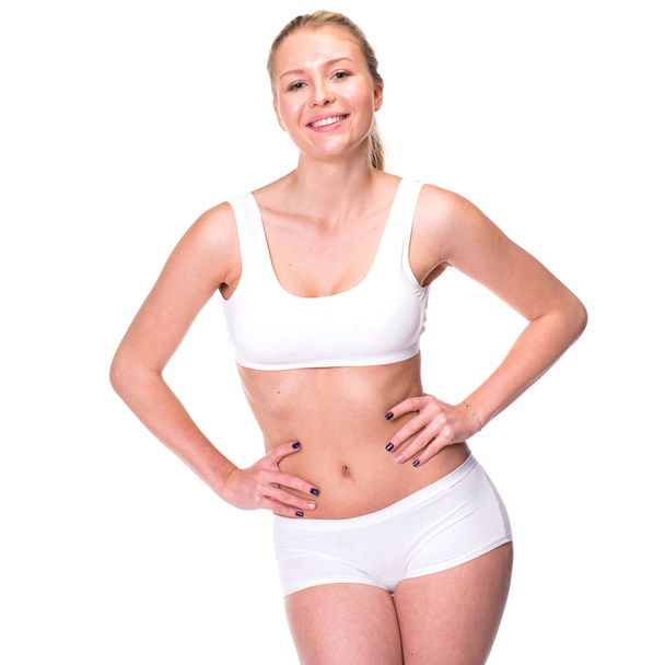 Portrait of a young blonde woman in sportswear without makeup. Sexy beautiful model in white fitness clothing, isolated on white background - Φωτογραφία, εικόνα