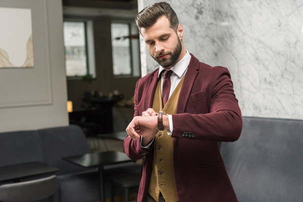 serious businessman in formal wear looking at watch  - Φωτογραφία, εικόνα