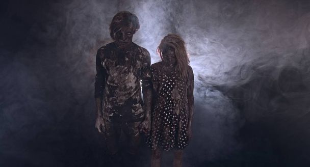 portrait of zombies together against dark misty background - Фото, изображение