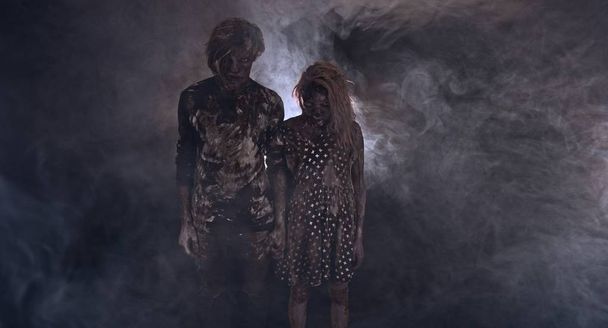 portrait of zombies together against dark misty background - 写真・画像