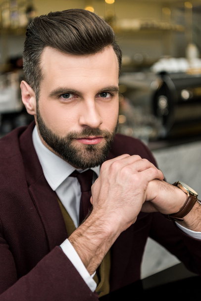 portrait of handsome businessman in formal wear with folded hands looking at camera - Фото, зображення