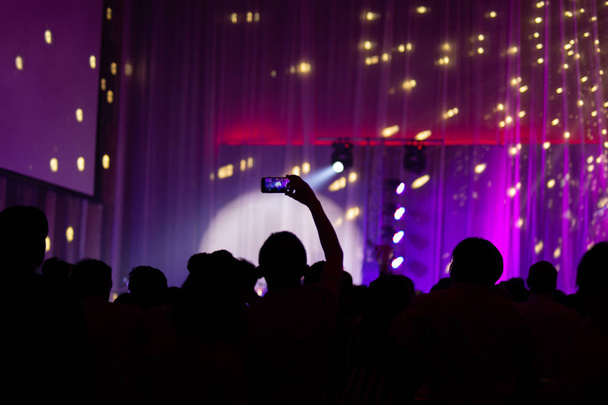 Silueta de la mano tomando fotos desde el teléfono celular en concierto en vivo borrosa
 - Foto, Imagen