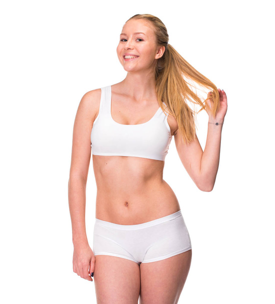 Portrait of a young blonde woman in sportswear without makeup. Sexy beautiful model in white fitness clothing, isolated on white background - Φωτογραφία, εικόνα