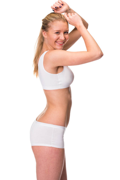 Portrait of a young blonde woman in sportswear without makeup. Sexy beautiful model in white fitness clothing, isolated on white background - Foto, afbeelding
