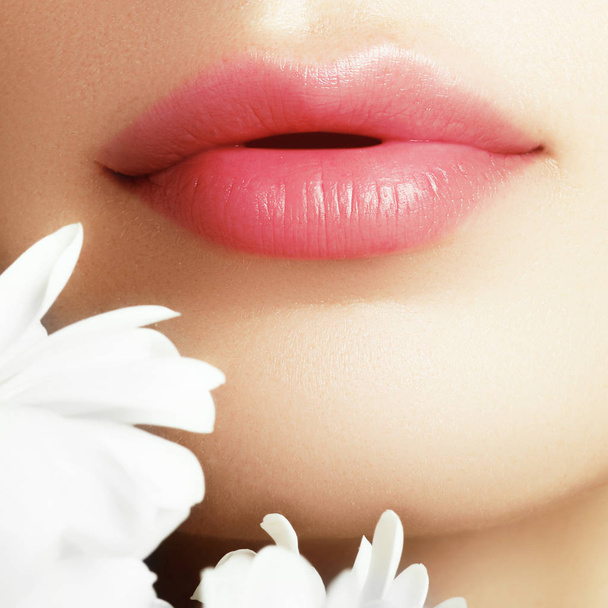 Cosmetica, make-up en trends. Heldere lipgloss en lippenstift op de lippen. Close-up van mooie vrouwelijke mond met rode lip make-up. Prachtige deel van het vrouwelijke gezicht. Perfect schone huid - Foto, afbeelding