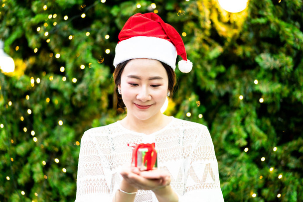 portrait of smiling beautiful young Asian woman with gift on the festive Christmas fair - vintage effect filter - Foto, Imagem