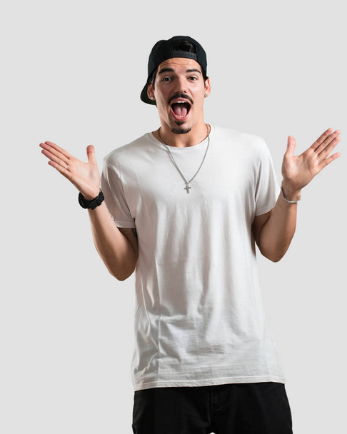 Jonge rapper man schreeuwen gelukkig, verrast door een aanbieding of promotie, gapende, springen en trots - Foto, afbeelding