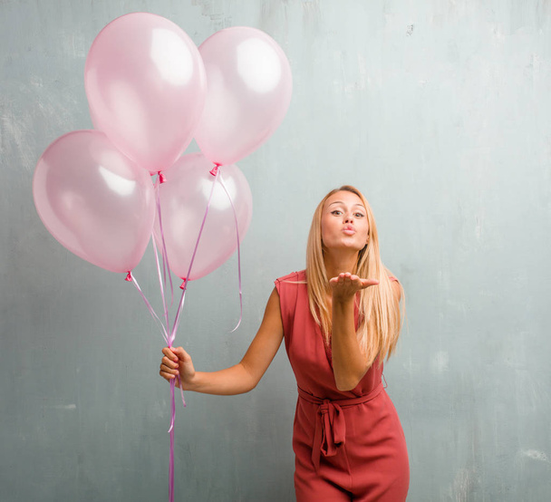 Portrait of elegant young blonde woman sending a kiss, celebrating new year or another event, holding balloons. - Foto, Imagen