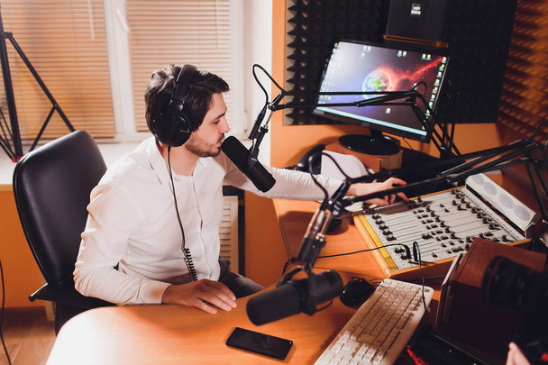 Portrait of radio host using sound mixer on table in studio. - Фото, изображение