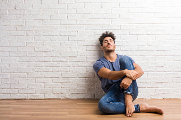 Young natural man sit on a wooden floor proud and confident, pointing fingers, example to follow, concept of satisfaction, arrogance and health - Photo, Image