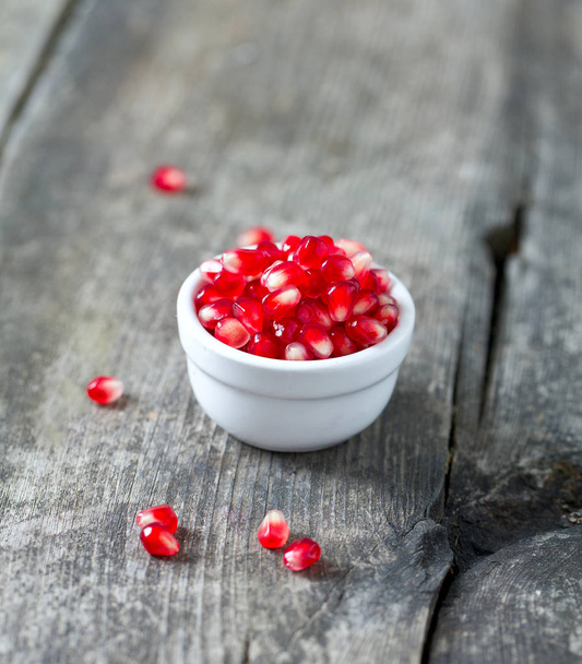 pomegranate seeds on wooden surface - Фото, изображение