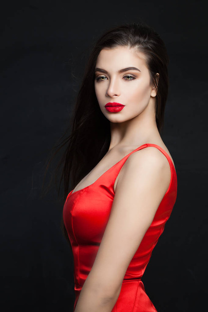 Sexy fashion model brunette met lang haar en rode lippen make-up. Perfecte vrouw op zwarte achtergrond - Foto, afbeelding