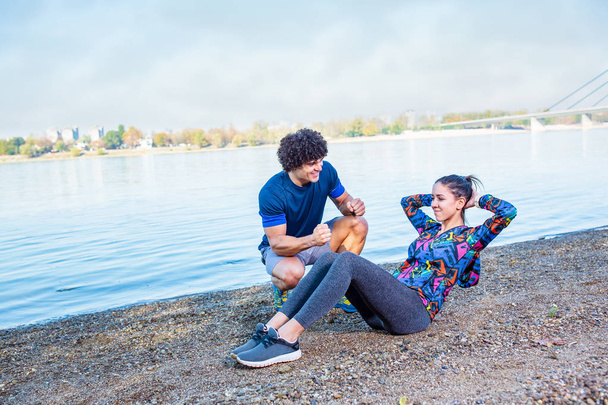 Você pode fazê-lo - instrutor de fitness ajudando a jovem fazendo sit-ups ao ar livre
 - Foto, Imagem