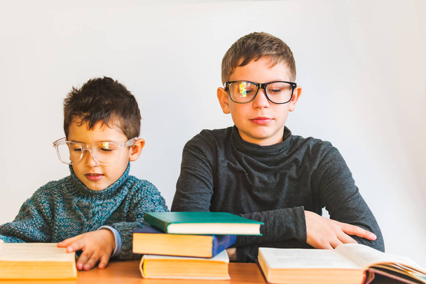 Kaksi silmälasipäistä poikaa lukemassa kirjoja
 - Valokuva, kuva