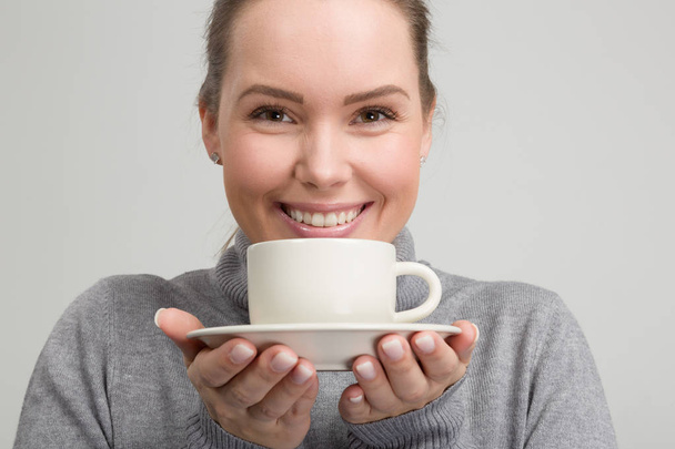Young beautiful woman with a cup of fresh coffee in her hand - Photo, Image