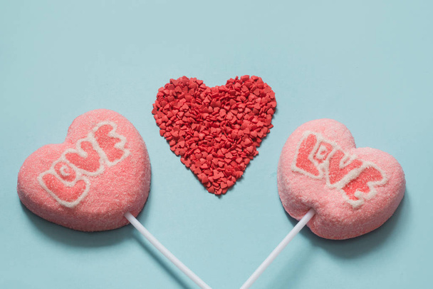 Couple valentine lollipops pink candy on stick with Love text on blue background. Funny concept. Close up. - Foto, Bild