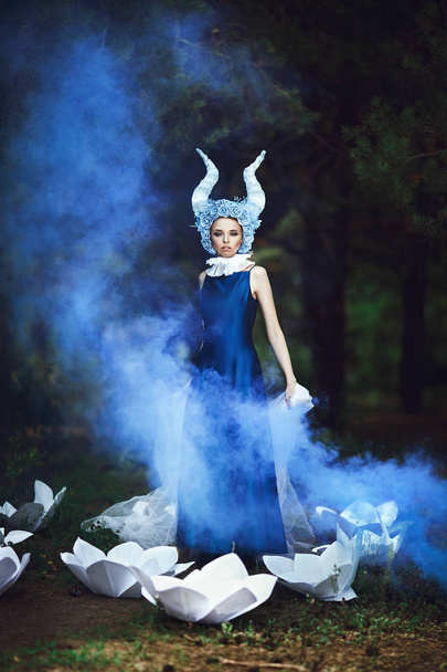 Beautiful model is posing in a forest with blue horns - Фото, зображення