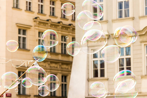 joyful colorful background lots of transparent soap bubbles background of a facade of a European house lots of airy light bullets - Фото, зображення