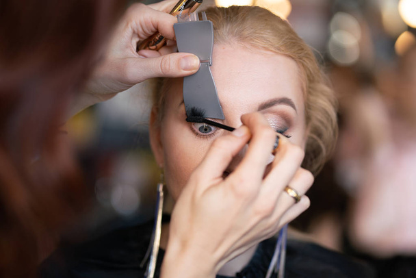 Professionelle Visagistin schminkt Schritt für Schritt das Gesicht einer Blondine - Foto, Bild