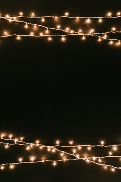 Christmas tree lights on dark table top. Rustic New Year black minimal background  - Photo, Image
