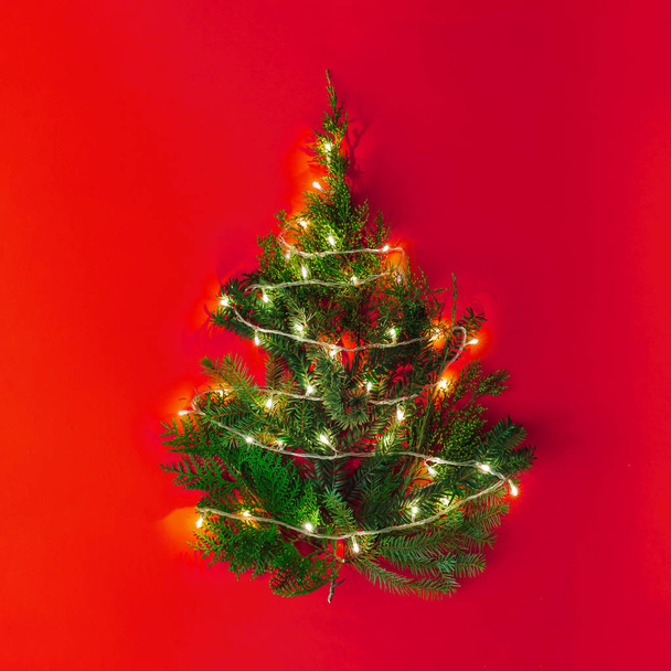 Christmas tree with lights on red table . Rustic New Year minimal background  - Φωτογραφία, εικόνα
