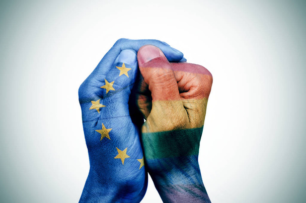 zbliżenie dłoni człowieka ułożyła wzorzyste z flagi Unii Europejskiej i tęczy flaga - Zdjęcie, obraz