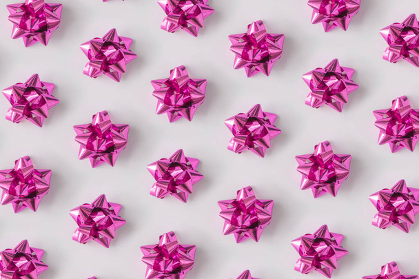 Πλαστικά ροζ διακοσμητικό χριστουγεννιάτικο δώρο τόξα σε ανοιχτόχρωμο φόντο, ιδέα το νέο έτος  - Φωτογραφία, εικόνα