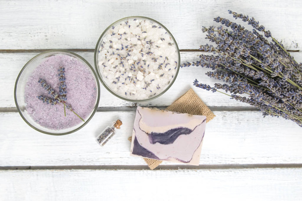 Natural herbal sea salt with aromatic lavender - perfect for relaxation. Cosmetic jars and bottles with salt, lavender flowers, bath bomb - Фото, изображение