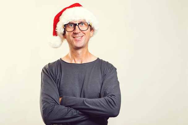 Όμορφος άνδρας φοράει γυαλιά και ένα καπέλο Χριστουγέννων. Ευτυχισμένος άνθρωπος Santa απομονωθεί σε λευκό, αντίγραφο χώρου. Ανέμελο νεαρό άνδρα στα γυαλιά απολαμβάνοντας την περίοδο των Χριστουγέννων. Ανθρώπους, τα Χριστούγεννα, πωλήσεις και ιδέα του τρόπου ζωής. - Φωτογραφία, εικόνα
