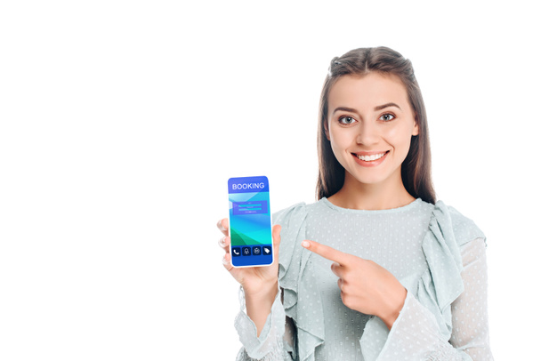 Lächelnde Frau zeigt Smartphone mit Buchungsaufschrift auf weißem Grund - Foto, Bild