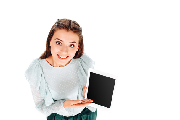 pohled z vysokého úhlu usmívající se žena ukazuje na tabletu s prázdnou obrazovkou izolované na bílém - Fotografie, Obrázek