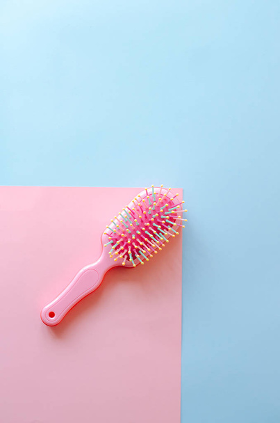 rosafarbener weiblicher Haarkamm auf blauem und rosa Hintergrund. - Foto, Bild