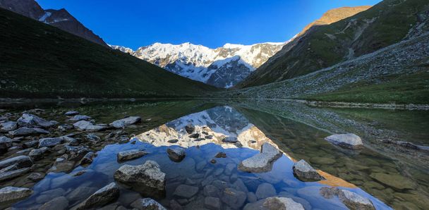 Spiegelung der schneebedeckten Gipfel in einem Bergsee. Blick auf den kaukasischen Hauptkamm. Kaukasisches Hochlandreservat. - Foto, Bild