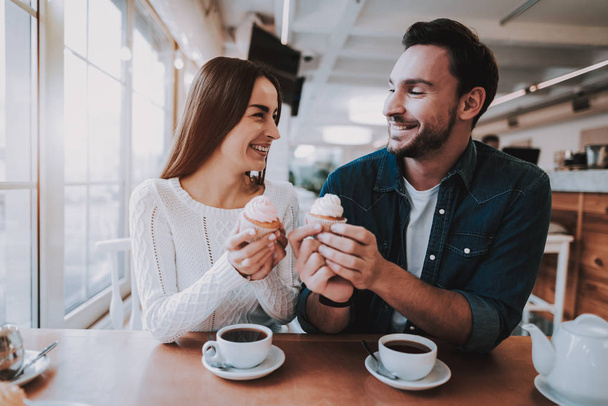 Couple Resting in Cafe. Couple is Beautiful Young Man and Woman. Couple is Eating Cakes and Drinking a Tea. Persons is Sitting at Table. People is Happy and Smiling. Sunny Daytime. - Fotoğraf, Görsel