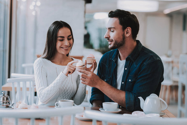 Couple Resting in Cafe. Couple is Beautiful Young Man and Woman. Woman is Touching a Man's Cake. Tea on Table. Persons is Sitting at Table. People is Happy and Smiling. Sunny Daytime. - Fotó, kép