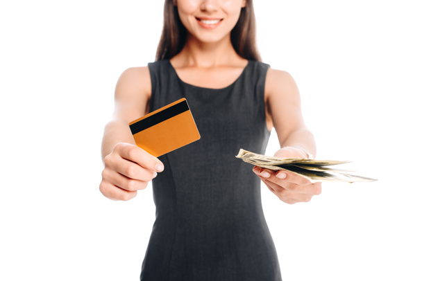 przycięte strzał uśmiechający się kobieta w czarnej sukience z karty kredytowej i gotówki na białym tle - Zdjęcie, obraz