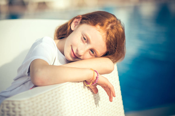 Souriant mignonne petite fille assise à la piscine le jour ensoleillé
. - Photo, image