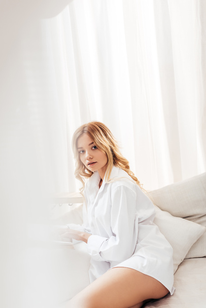 selective focus of pretty young woman with blonde hair looking at camera in bed  - Fotoğraf, Görsel