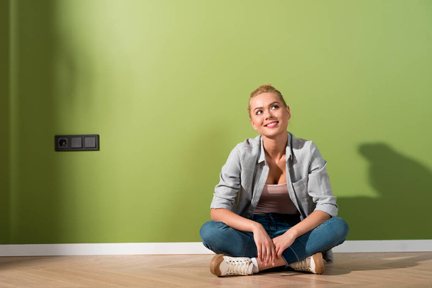 dreamy girl sitting on floor by green wall - Photo, image