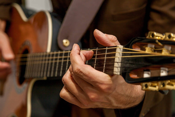 Close-up of the hands of a musician playing the guitar. The fingers of the musician are pressing the strings on the guitar. Musician playing bass guitar - Foto, afbeelding