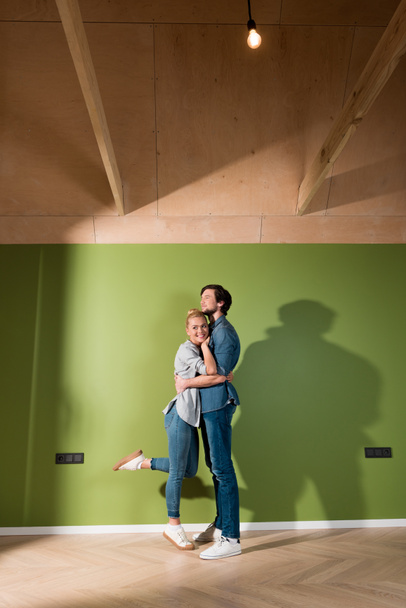 loving family couple hugging by green wall in apartment - Fotoğraf, Görsel