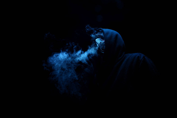 Mies mustassa hupussa pimeydessä, hämärässä, käsitteet vaara, rikollisuus kauhu
 - Valokuva, kuva