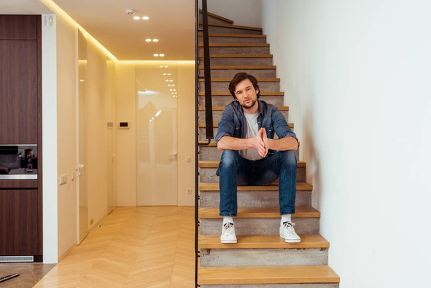 handsome man sitting on stairs and looking at camera - Foto, Imagem
