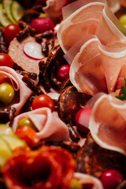 Мясо блюдо с выбором вкусной салями, ветчины, свежих колбас и трав
 - Фото, изображение