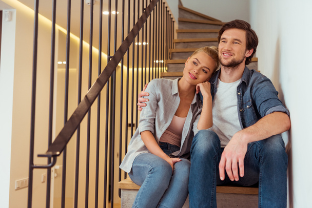 sonriente pareja sentado en escaleras en casa
 - Foto, imagen