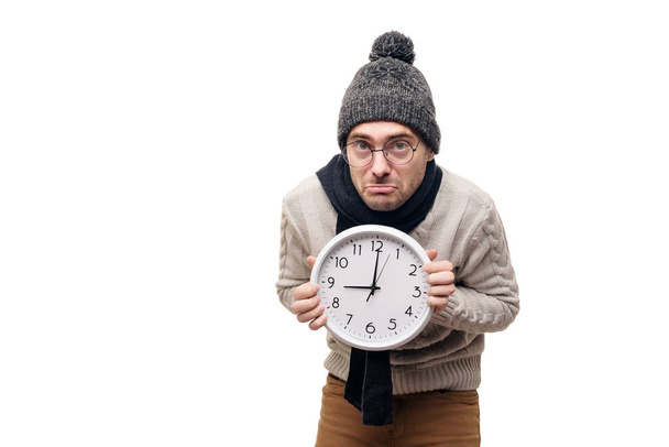 Sick Man with big wall clock in hands in a warm hat. White isolated background. Time to take medicine - Fotoğraf, Görsel