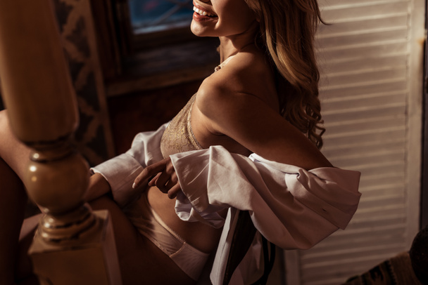 partial view of woman in white shirt and lace lingerie posing on chair - Photo, image