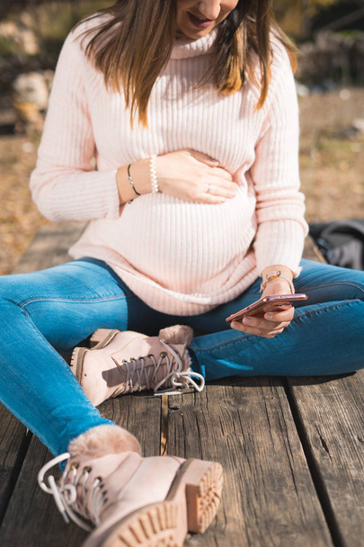 Pregnancy, motherhood, technology, people and expectation concept. happy pregnant woman with smartphone outside. - Photo, Image