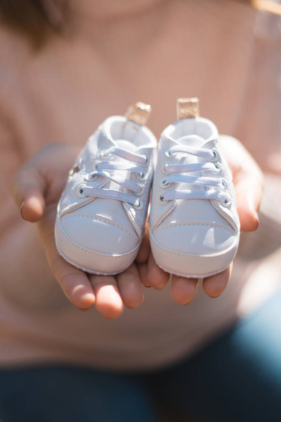 Pregnant woman belly holding baby shoes. Healthy pregnancy. - Fotó, kép