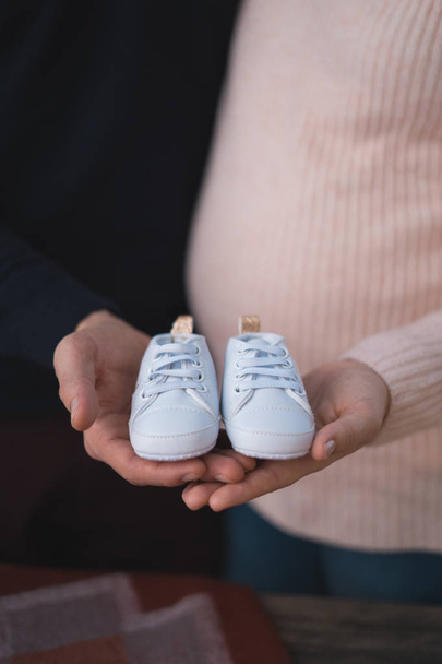 Husband and pregnant woman holding baby shoes, closeup - Foto, Imagen